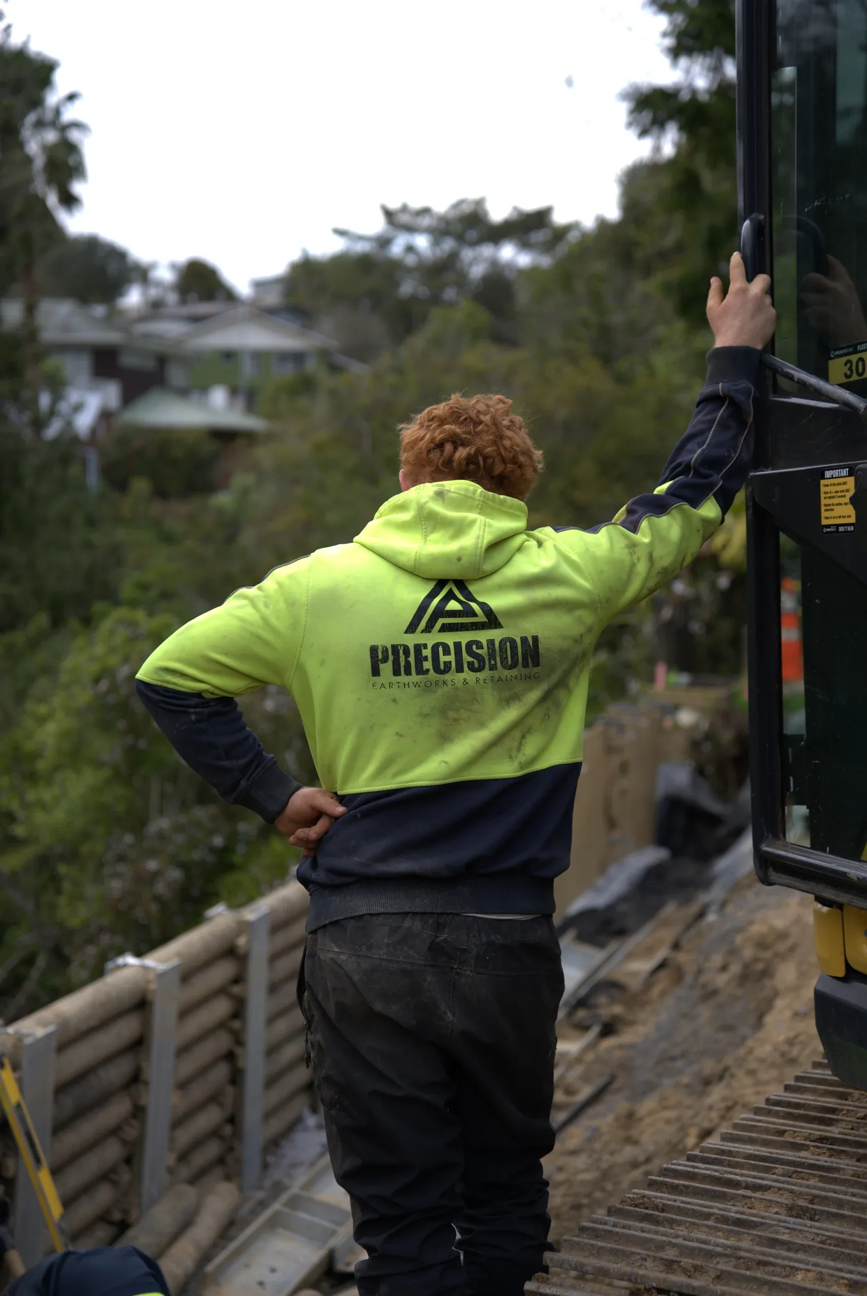 Precision Earthworks crew member looking out over the finished retaining wall and the property below.