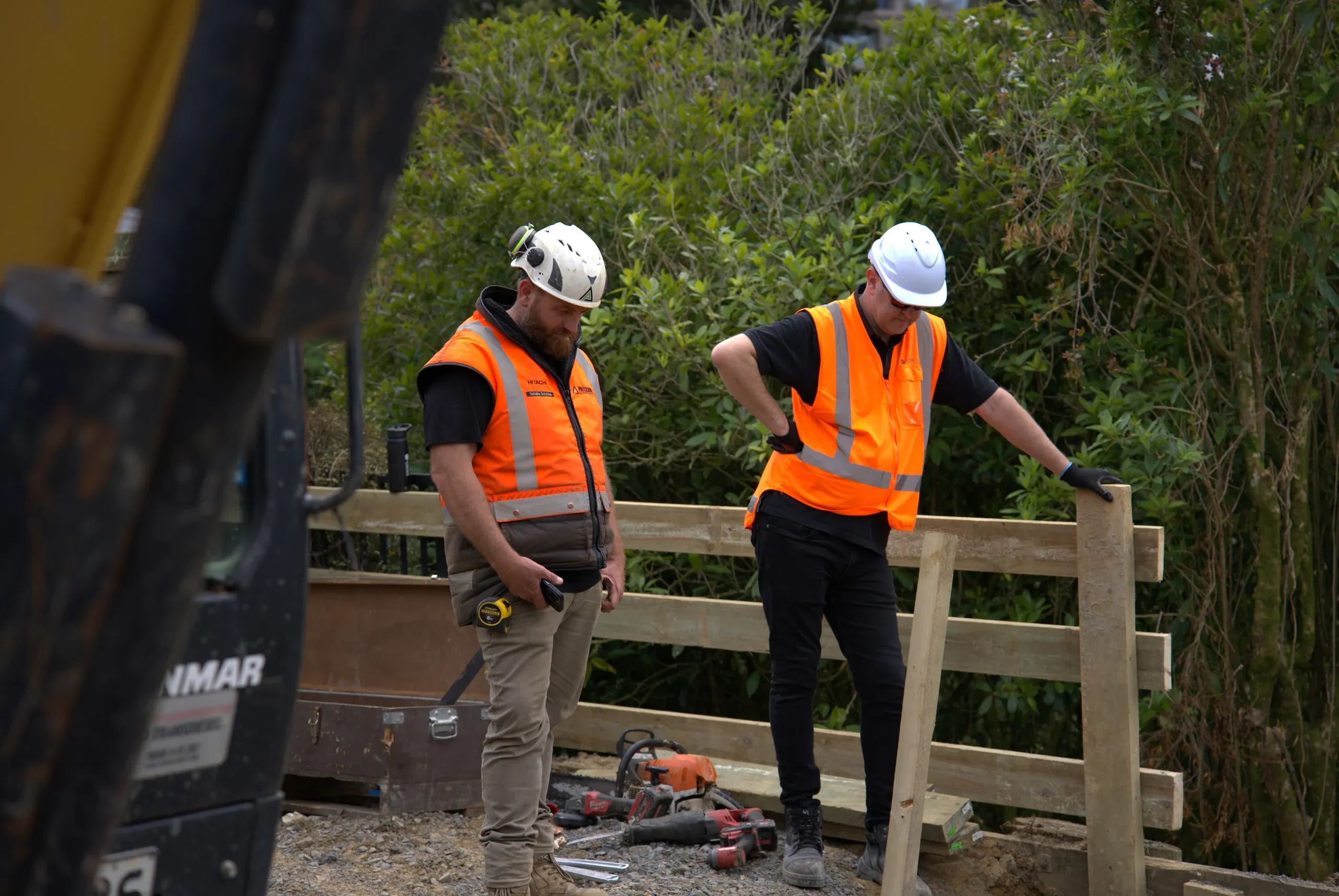 Crew fitting the timber post-and-rail barrier along the top of the completed wall.