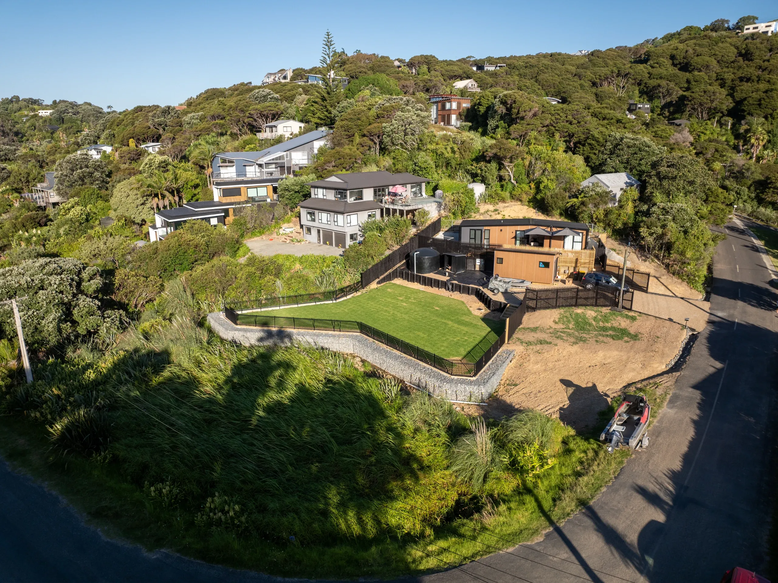 Oblique aerial of the finished terrace, the gabion wall wrapping the new lawn above the driveway.
