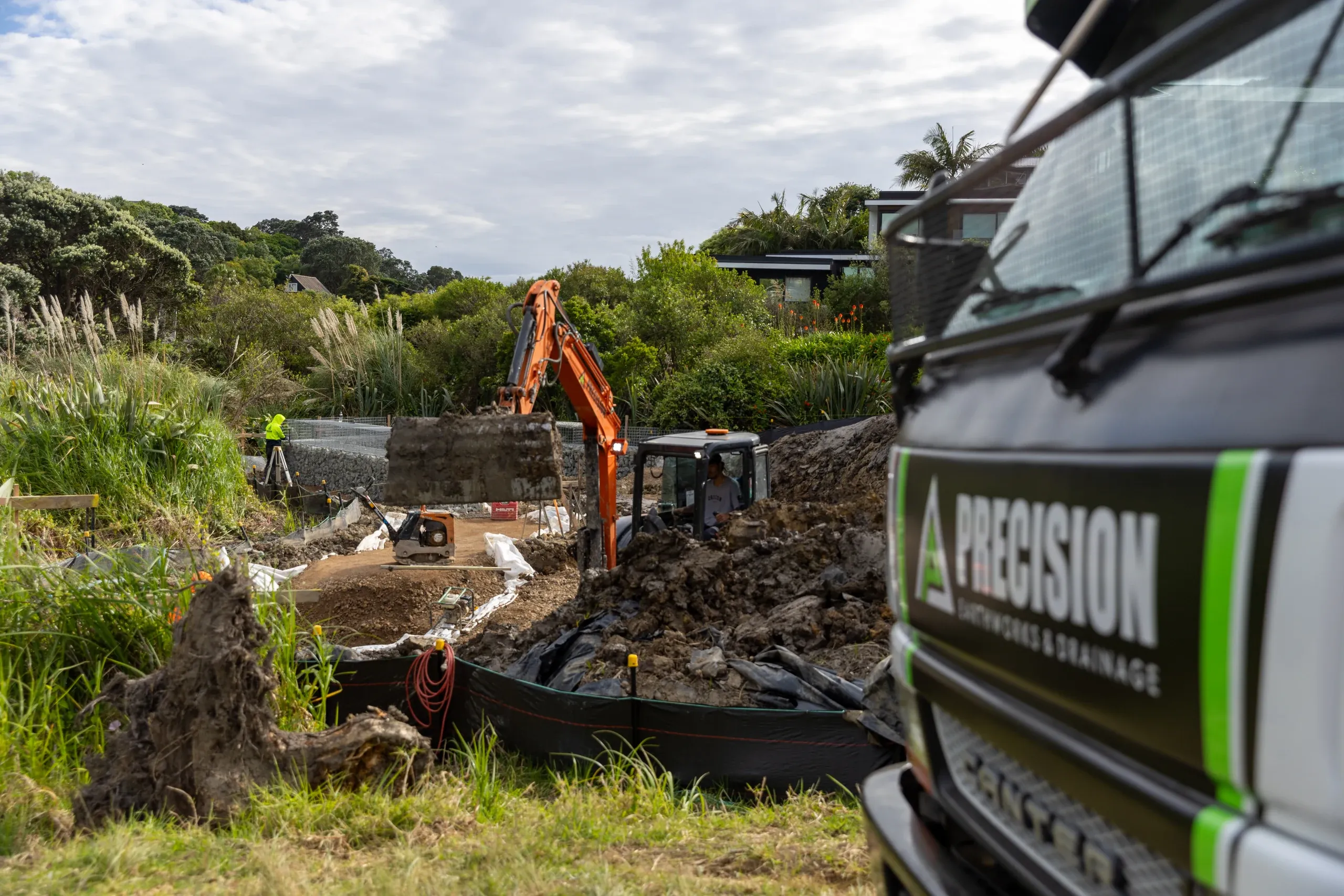 Crew and truck on the cut platform, drainage and retaining works underway across the terrace.
