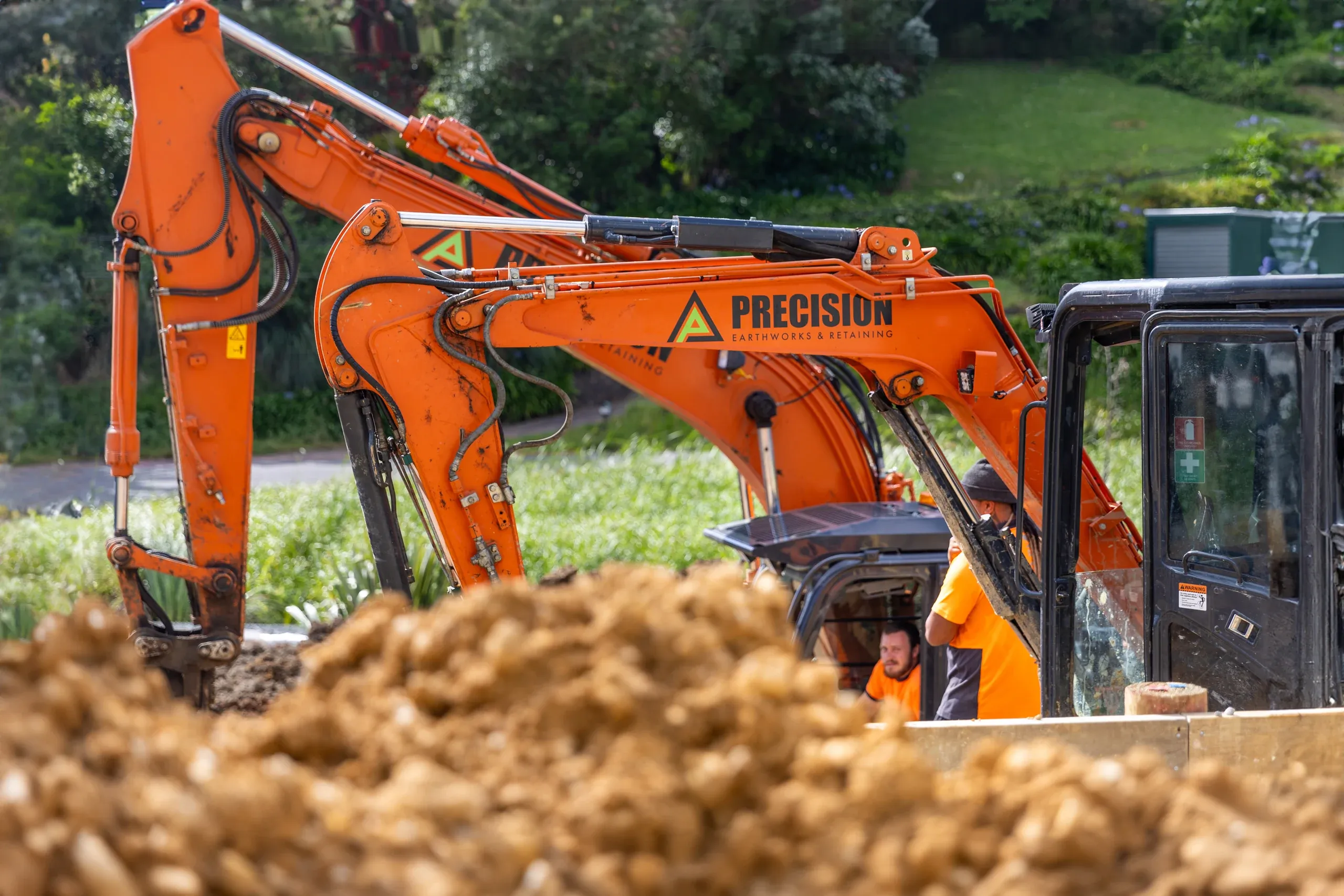 The excavator arm reaching over a freshly turned spoil heap on the terrace platform.