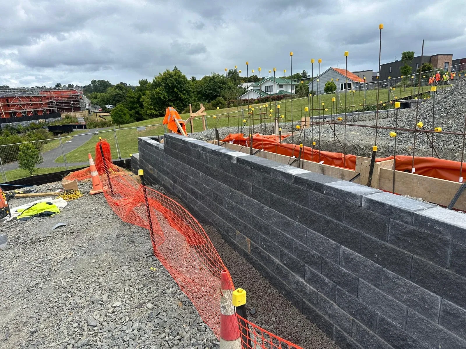 Capped Keystone block wall with foundation reinforcing and formwork set out on the platform above it.